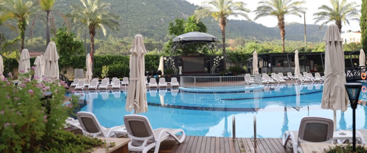 Blick auf den entspannten Poolbereich vom Hotel Meder Resort, umgeben von Palmen und mit Blick ind ie grüne Natur.